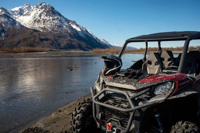 A red ATV parked by a lake with mountains in the background. 2