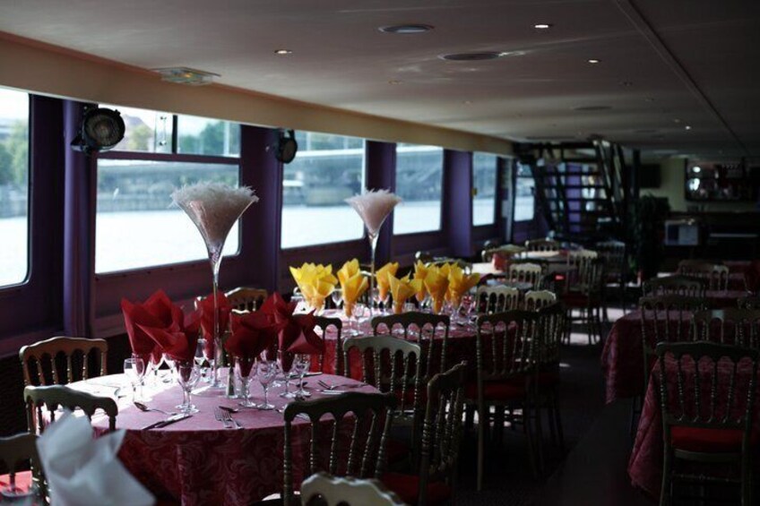 A dining area with tables set for service, chairs, and a view of a river through large windows. 3