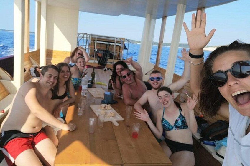 A group of people on a boat with a wooden deck, surrounded by water. 2