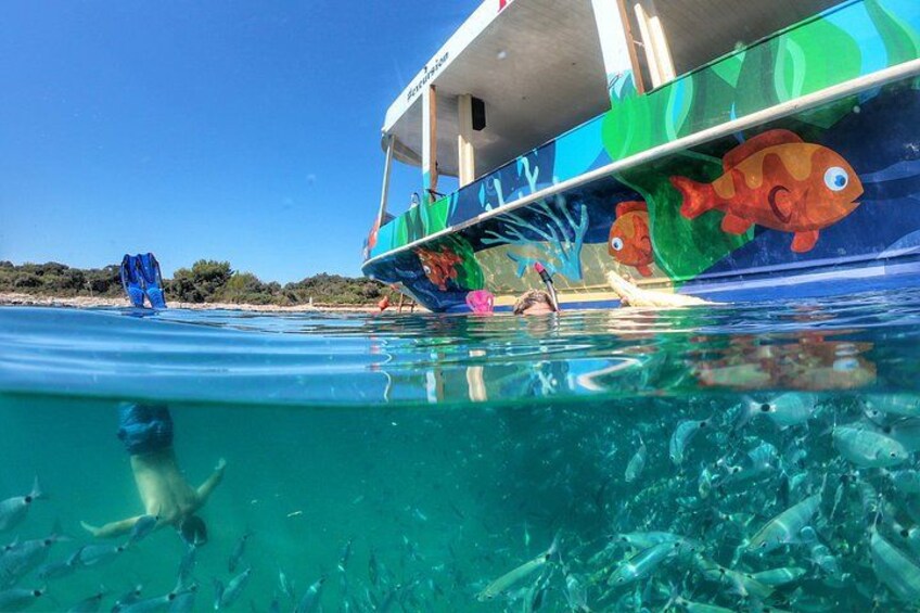 A boat with colorful fish designs on its side, partially submerged in clear blue water. 1