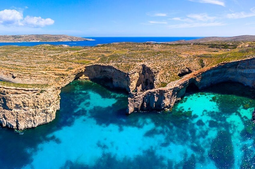 A coastal landscape with a prominent rock formation and clear turquoise waters. 2
