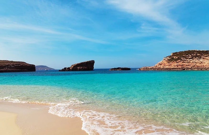 Un mar turquesa transparente, una playa arenosa y afloramientos rocosos. 4