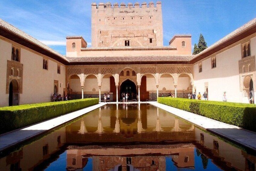 A courtyard with a reflective pool, arches, and a large tower. 2