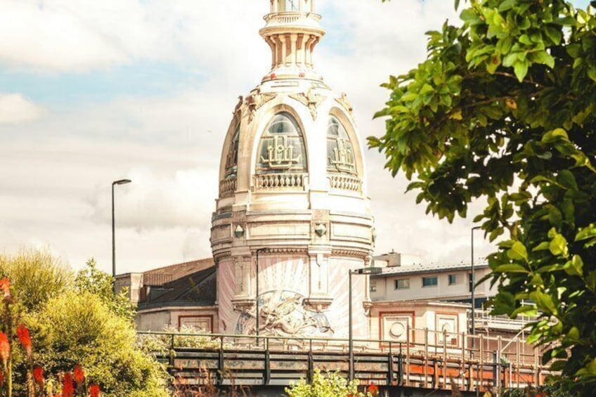 A historic building with a dome and statues, surrounded by greenery and a bridge. 2