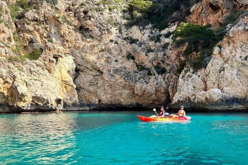 A kayak on turquoise water with rocky cliffs in the background. 1