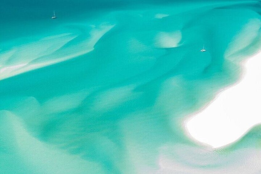 A turquoise ocean with two sailboats. 3
