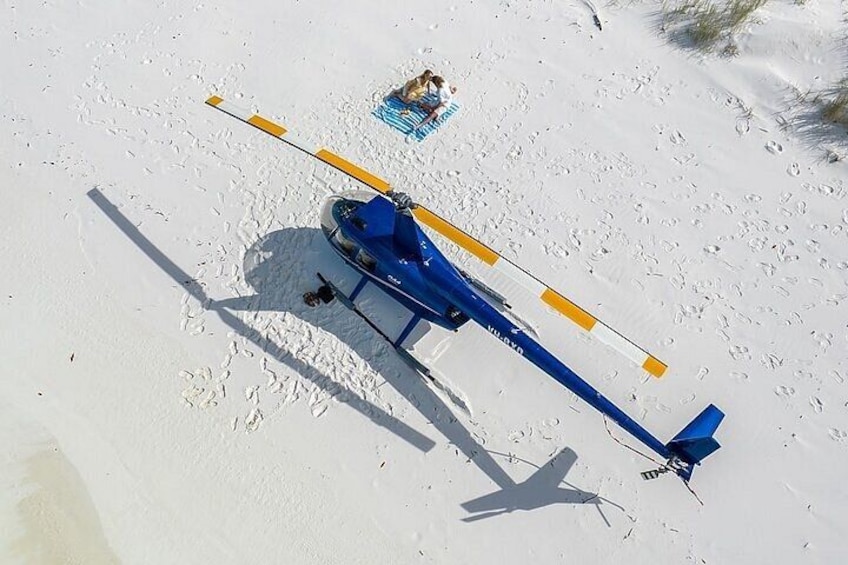 A blue helicopter with yellow stabilizers parked on a snowy surface. 1