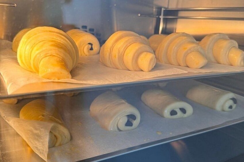 A bakery display with croissants and other pastries. 2