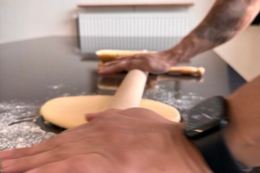A person rolling dough on a floured surface. 5