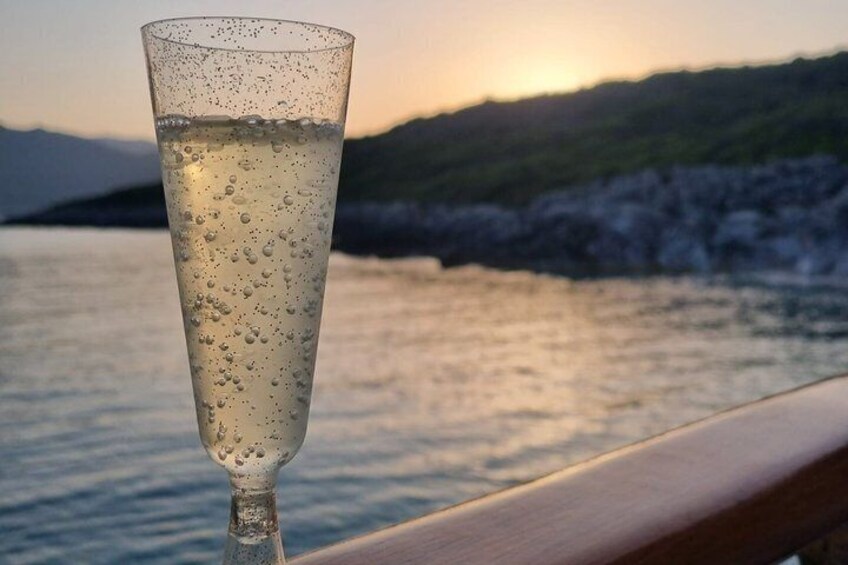A glass of water with bubbles, a wooden railing, and a body of water with a hilly landscape in the background. 3