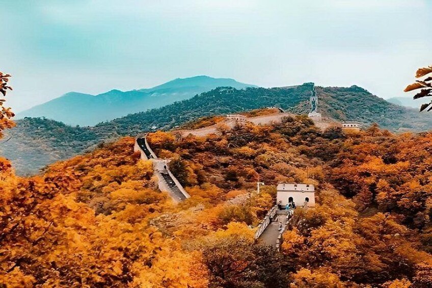 A winding road through a mountainous area with autumn foliage, a small building, and distant mountains. 2