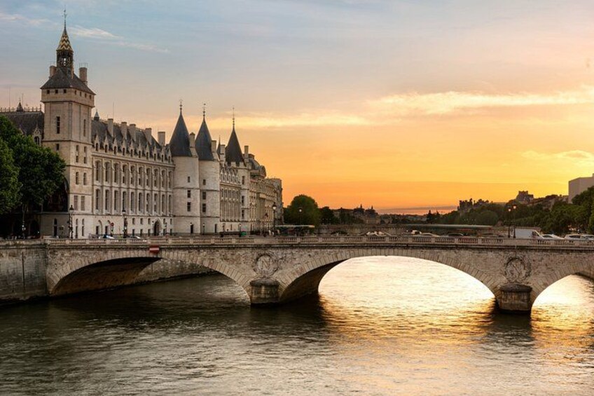 A stone bridge over a river with a historic building on the left. 4