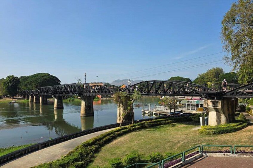 A steel bridge over a river, surrounded by greenery and a small boat dock. 4