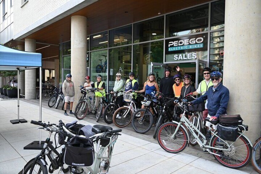 A group of cyclists standing outside a store with bicycles. 4