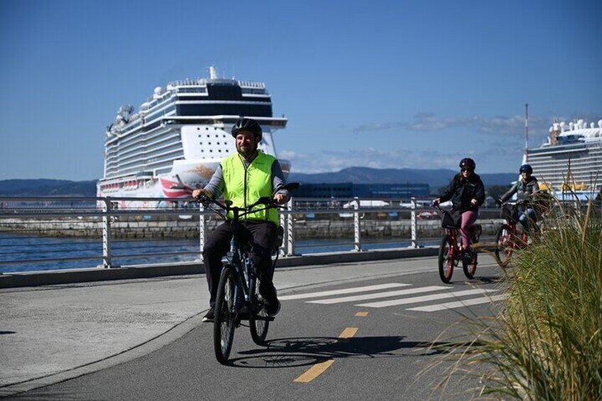 Two cyclists on a road with a cruise ship in the background. 2
