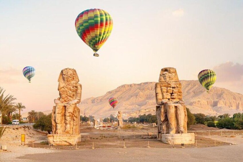 Ancient Egyptian statues, a desert landscape, and hot air balloons. 1