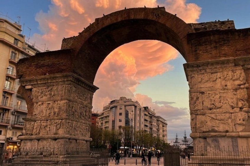 An ancient stone archway with a building in the background. 1