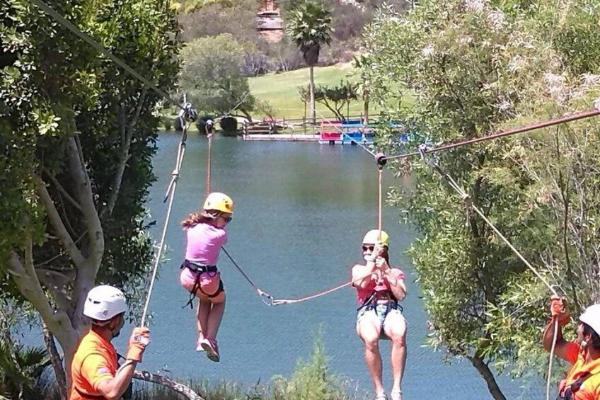 A zip-lining activity over a body of water with participants wearing helmets and harnesses. 5