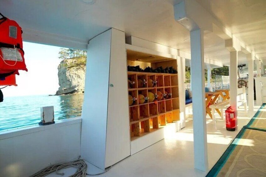A boat interior with a view of the sea, a shelf with shoes, and a life jacket hanging. 4