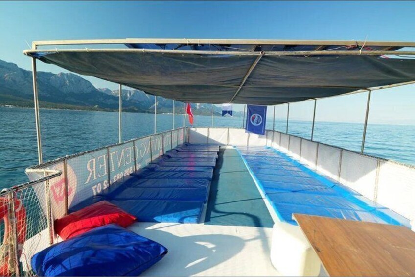 A boat deck with blue cushions, a table, and a covered area. 3