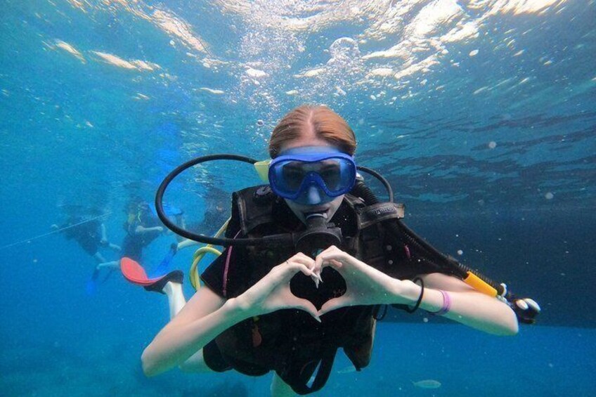 A person underwater making a heart shape with their hands. 1