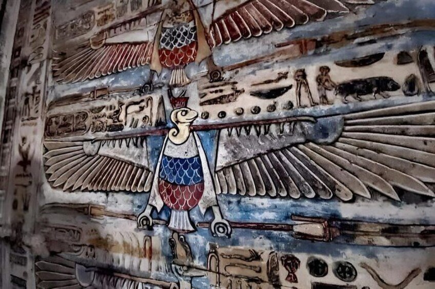 A wall with ancient Egyptian hieroglyphs and a central figure of a bird with outstretched wings. 4