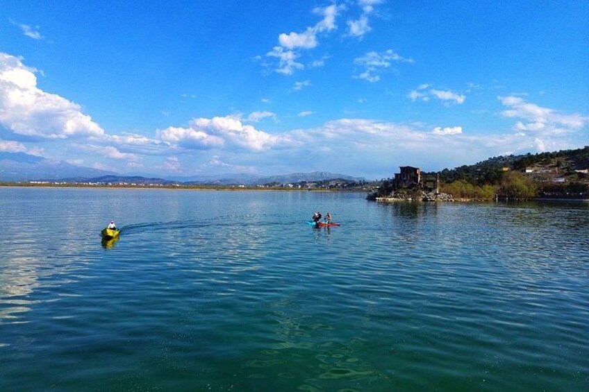 A calm lake with kayaks, a distant building, and a clear sky. 2