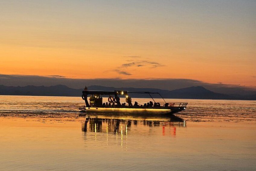 A boat on calm water during sunset with mountains in the background. 2