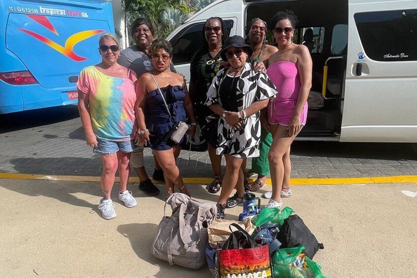 A group of people standing in front of a bus with luggage and bags. 4