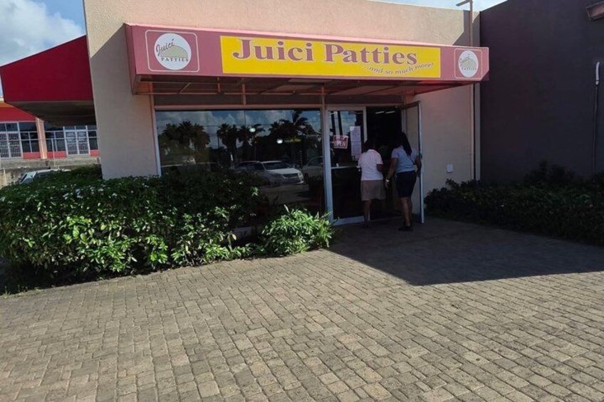 A storefront named Juici Patties with a red awning and a glass door. 3