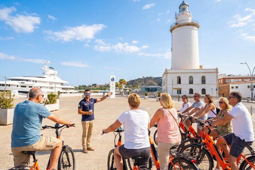 Un grupo de personas en bicicletas, un yate blanco y un faro al fondo. 3