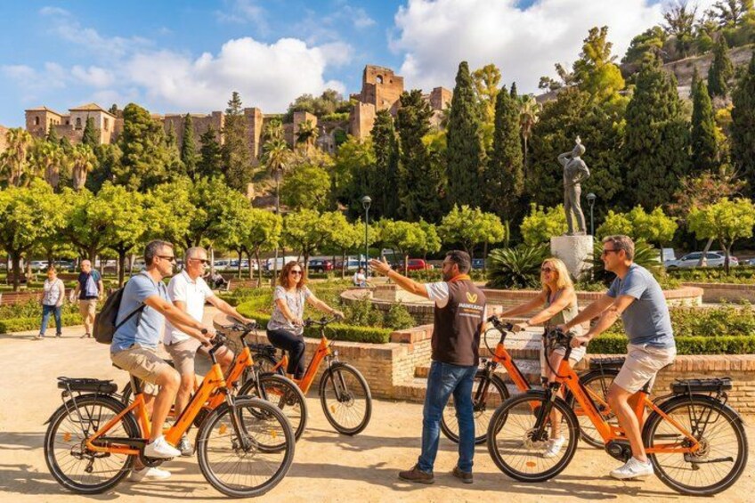 Un groupe de personnes à vélo dans un parc, avec une statue et des bâtiments historiques en arrière-plan. 2