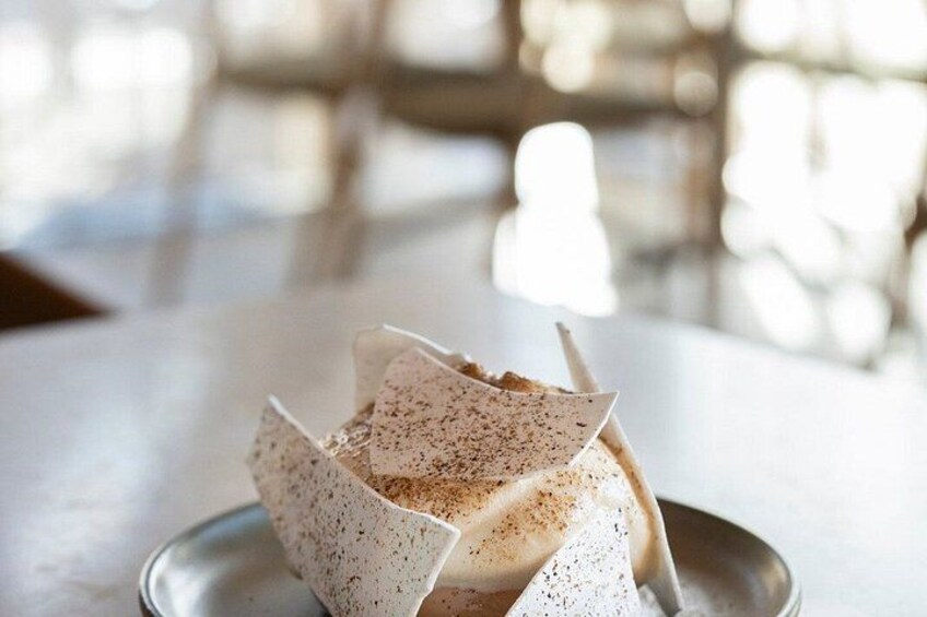A dessert in a paper cup on a metal plate. 4