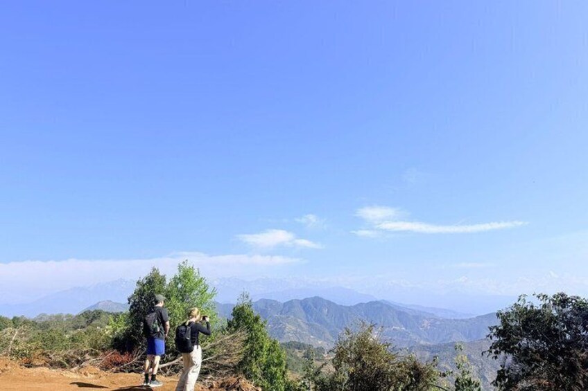 Two people hiking on a mountain trail with a view of distant mountains under a clear sky. 5