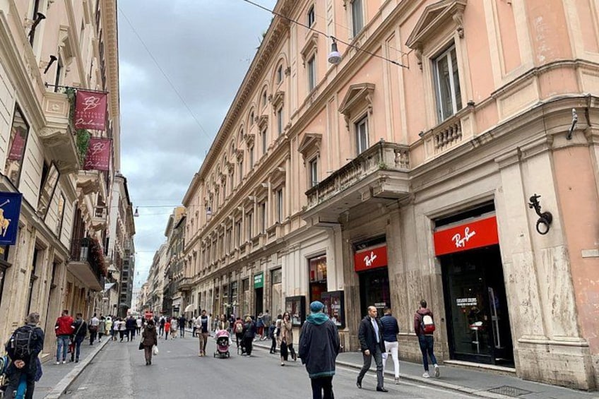 A busy street with pedestrians, shops, and classic architecture. 3