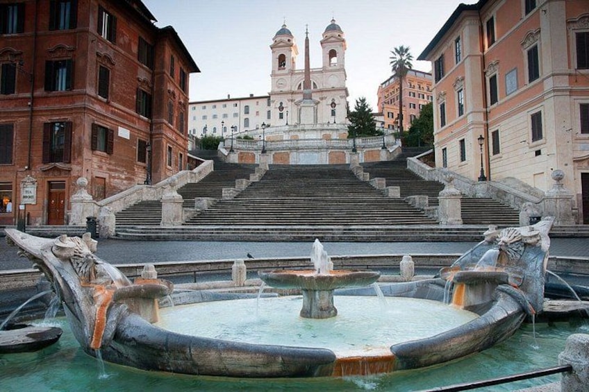 A historic fountain with statues, a staircase leading to a bell tower, and surrounding classical architecture. 5