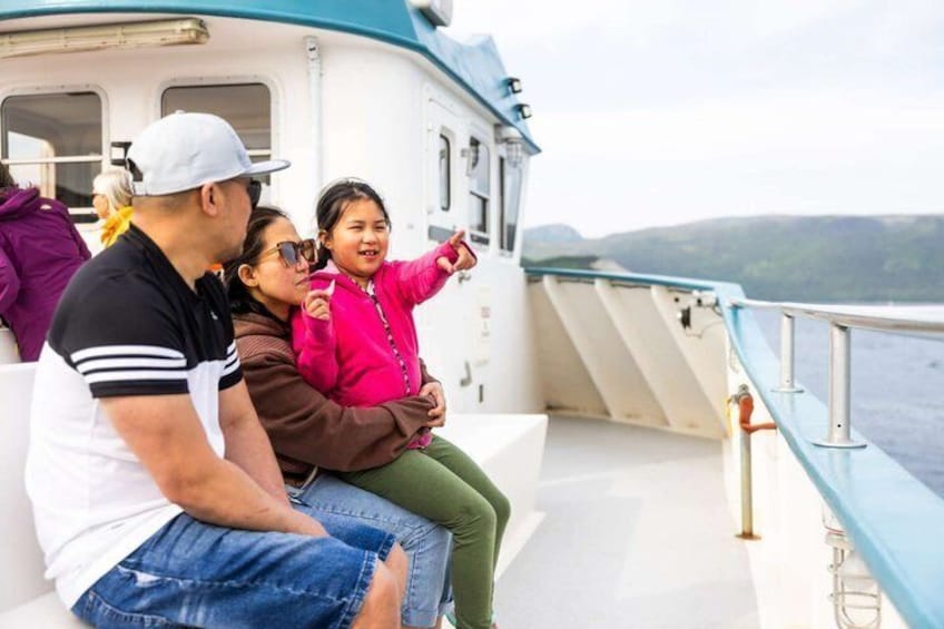 A family on a boat with a view of the water and hills in the background. 5