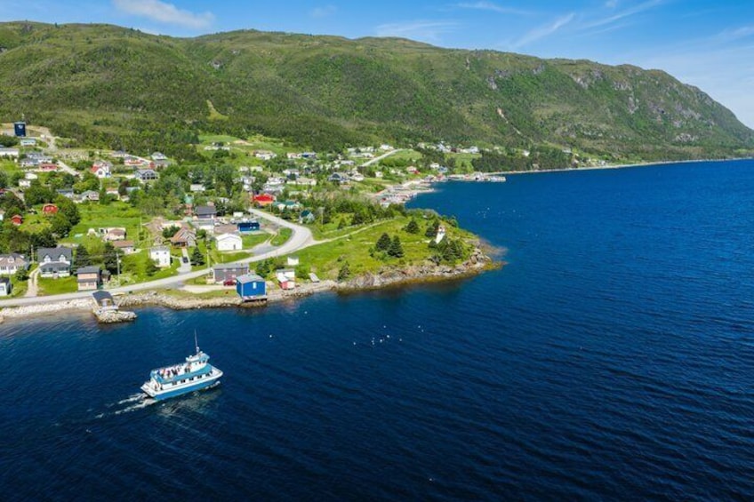 A coastal town with a boat on the water, surrounded by green hills. 4