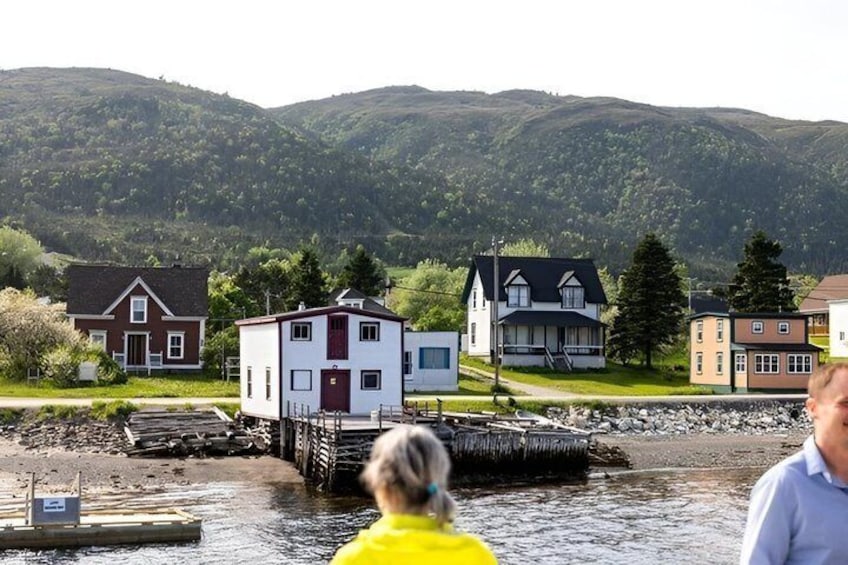 A waterfront with houses, a dock, and a mountain backdrop. 3