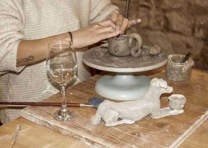 A person sculpting a ceramic teapot on a pottery wheel. 3