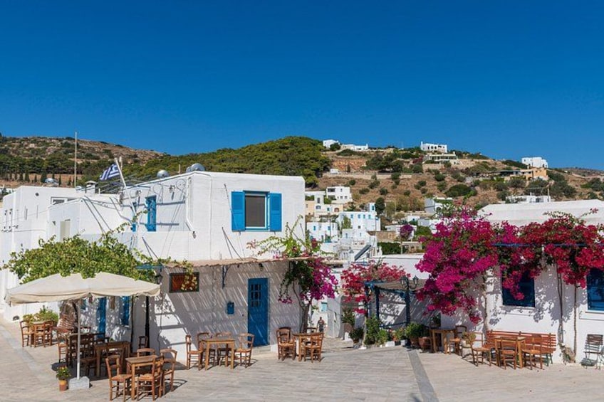 A coastal village with white buildings, blue shutters, and pink bougainvillea. 2