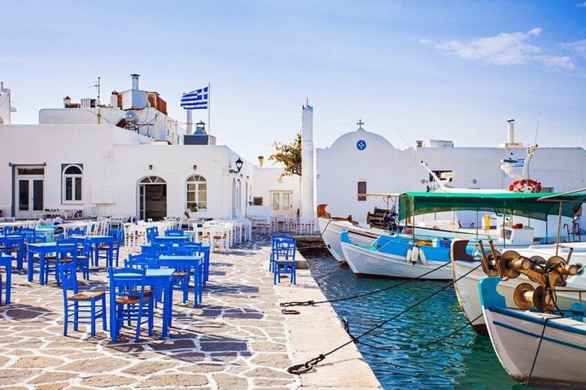 A harbor with white buildings, blue chairs, and boats. 3