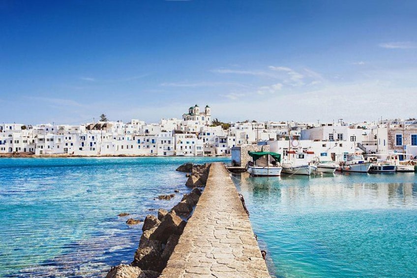 A coastal town with white buildings, a stone pier, and boats in the water. 4