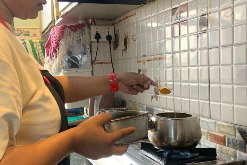 A person cooking in a kitchen with a pot on a stove and a bowl in hand. 5
