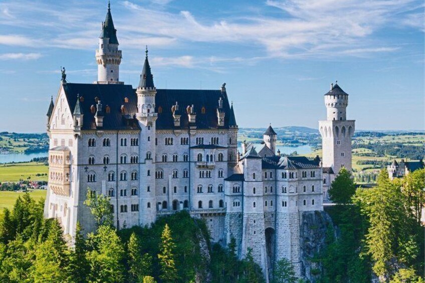 A large castle with multiple towers and turrets, surrounded by lush greenery and a clear sky. 5