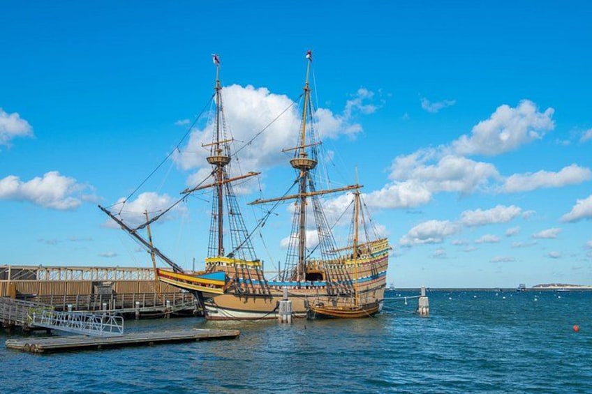 A large sailing ship docked at a pier with a clear blue sky and calm sea. 5