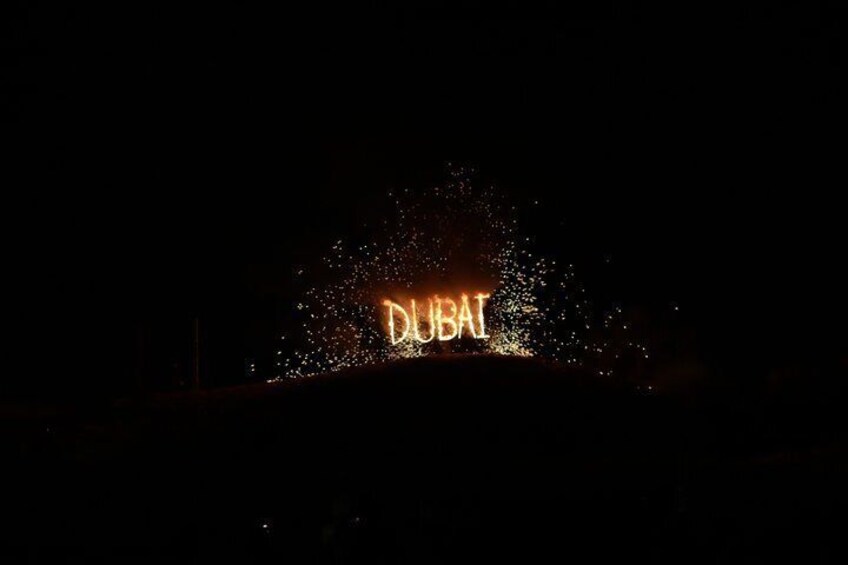 A nighttime scene with the illuminated text 'DUBAI' against a dark background. 3