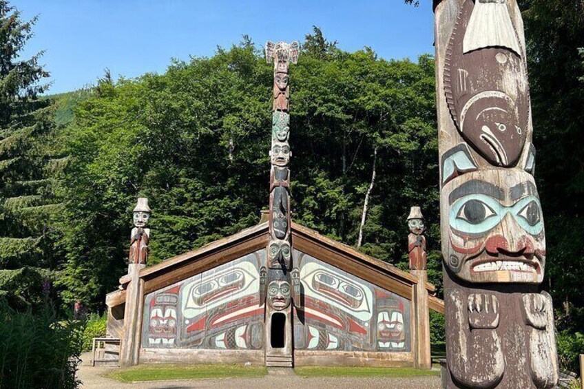 A totem pole and a painted structure with indigenous artwork. 2
