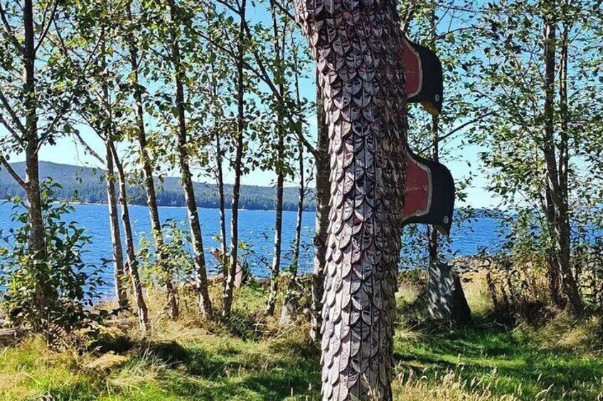 A tree with a carved wooden figure, a lake, and a mountain in the background. 3