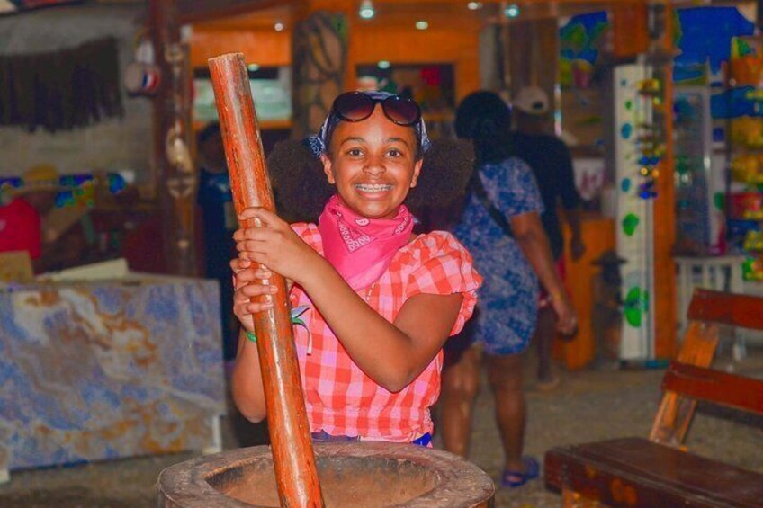 A person holding a wooden object in a market setting with colorful items and a rustic background. 3